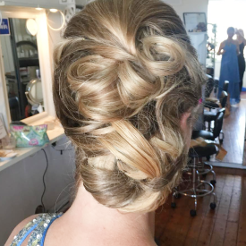 Elegant braided hairstyle from the back in a salon. A woman with an intricately braided blonde updo hairstyle in a salon setting.
