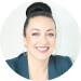 A professional headshot of a smiling woman with dark hair styled in a bun, wearing hoop earrings and a teal blazer.