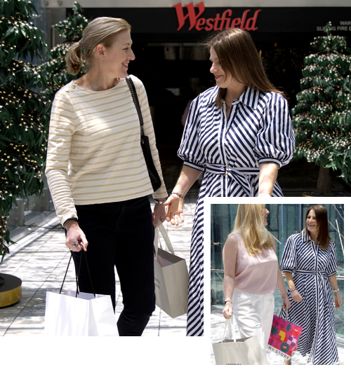 Happy women enjoying a personalised shopping experience at Westfield and outdoors. Two women smiling and holding shopping bags while walking through a Westfield shopping centre decorated with festive lights. One woman is wearing a striped sweater, and the other is in a blue and white striped dress. An inset shows two women walking outdoors with shopping bags, one in a pink sleeveless top and the other in the same striped dress.