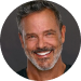 A smiling man with salt-and-pepper hair and a well-groomed beard in a circular cropped professional headshot. He is wearing a black shirt against a dark grey background.