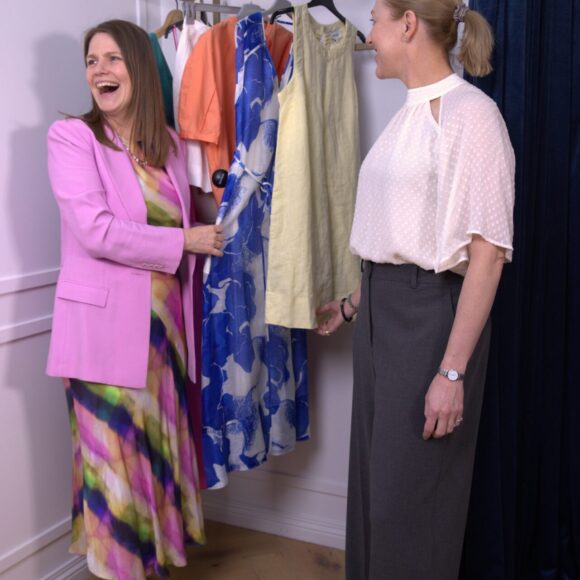 Personal stylist and client laughing while selecting colourful clothes from a rack