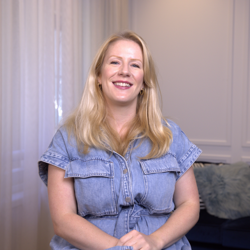 Hair Style & Colour Consultation – Effortless Look with Bold Accessories Woman with long blonde hair smiling while seated in a softly lit room