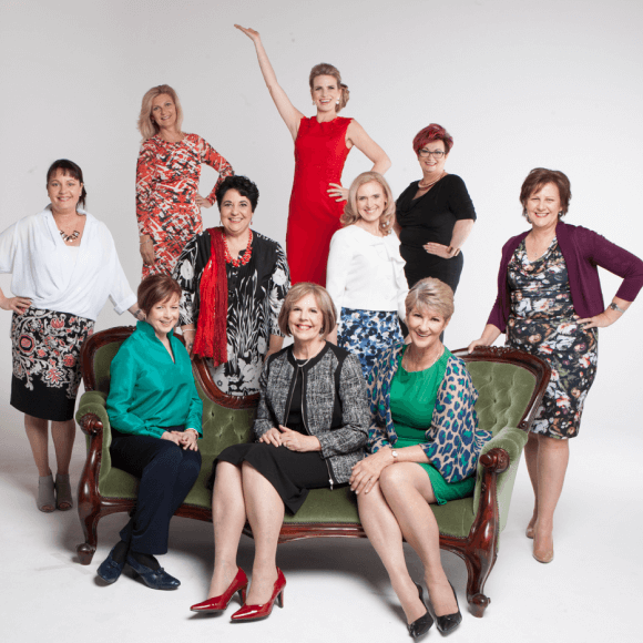 Ten women pose against a clean white backdrop, wearing vibrant patterns and expressive styles.
